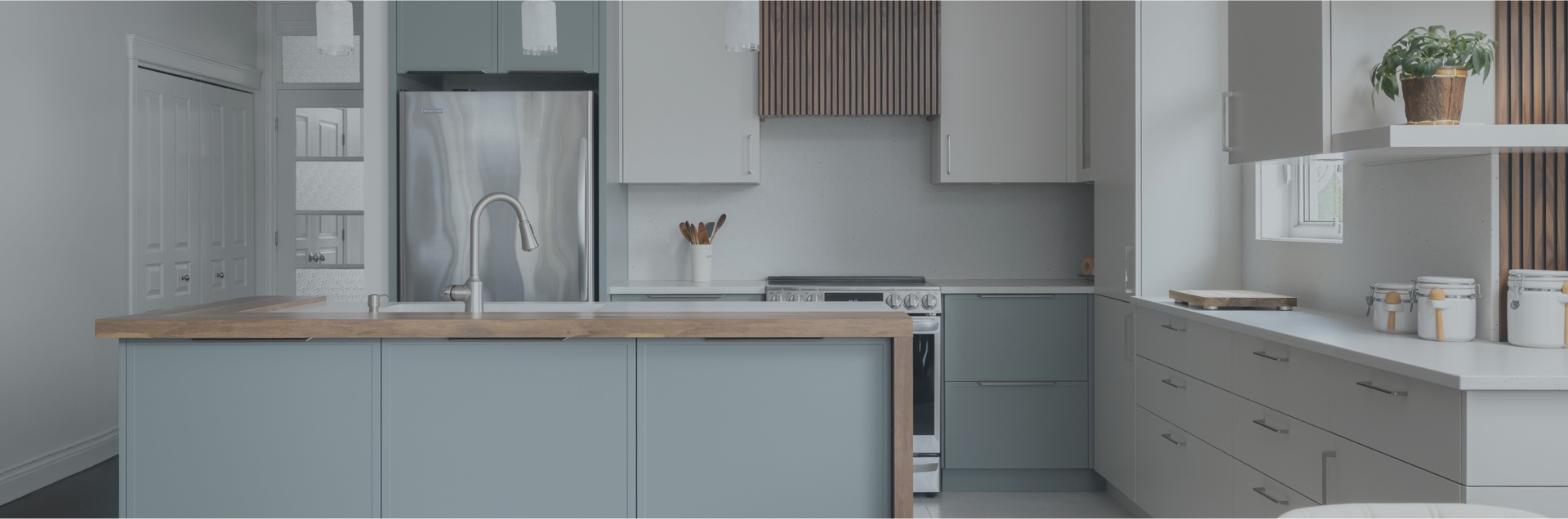 Cuisine moderne avec îlot central en quartz, meubles gris élégants et réfrigérateur encastré. Grand espace lumineux avec vue sur l’extérieur, créant une ambiance contemporaine et fonctionnelle.