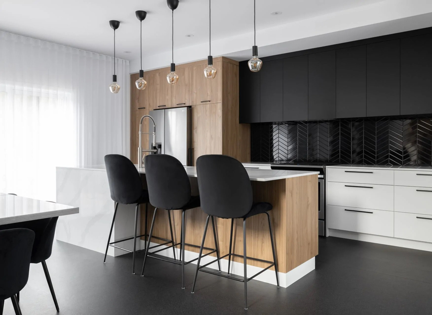 Cuisine moderne avec armoires en laminé européen, combinant finitions bois et noir mat, îlot central avec comptoir blanc et éclairage suspendu pour un design élégant et sophistiqué.