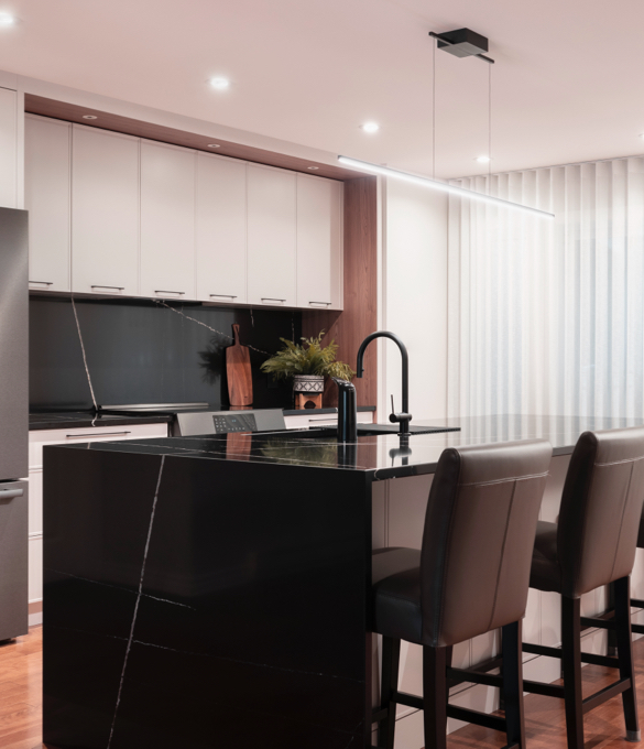 Modern kitchen designed by a kitchen designer, featuring a glossy black central island, high stools, and custom storage, combining elegance and functionality.