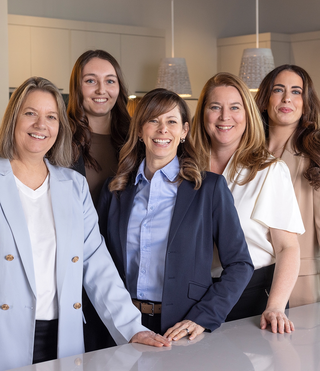A smiling kitchen designer takes notes in a showroom, surrounded by samples of cabinet fronts and materials for custom kitchen design.