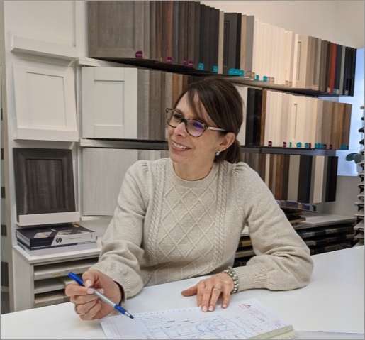 Conseillère en aménagement discutant d’un projet de salles de bain sur mesure devant un mur d’échantillons de finitions et de matériaux.