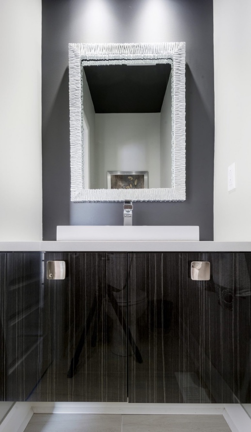 Meuble de salle de bain sur mesure noir laqué avec vasque blanche et miroir encadré argenté, créant un style moderne et élégant.