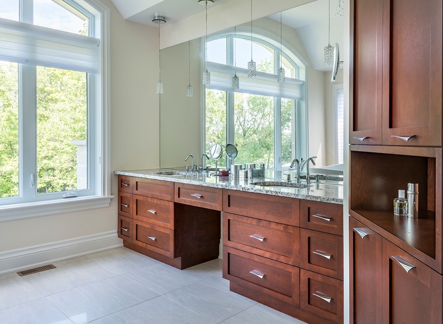 Salle de bain sur mesure avec mobilier en bois massif, plan en granit et grande coiffeuse double face à une fenêtre panoramique.